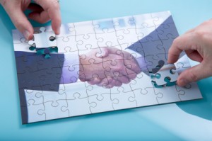 A jigsaw of a handshake being completed ny two hands.